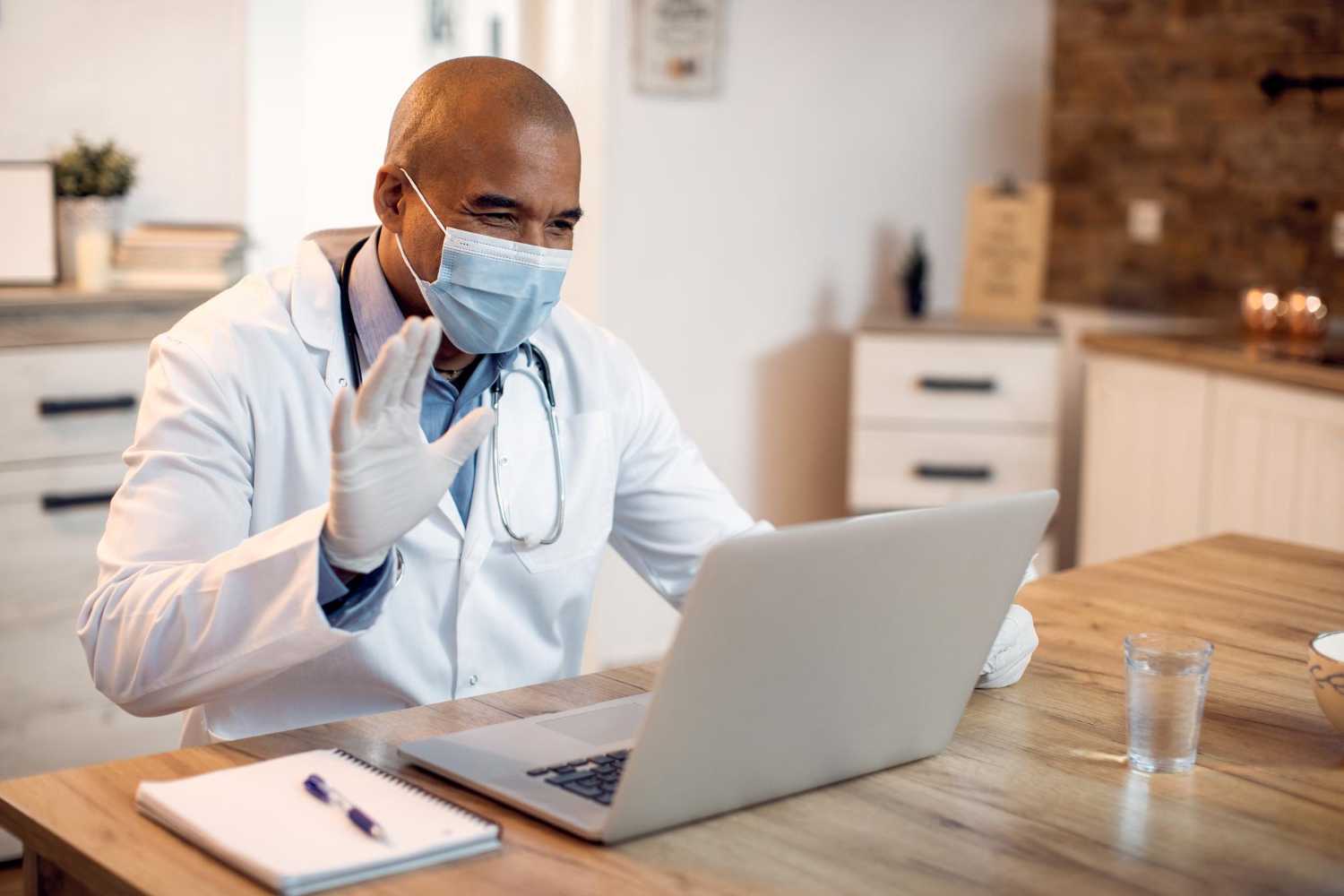 Médico sentado de frente para um computador em uma chamada de vídeo