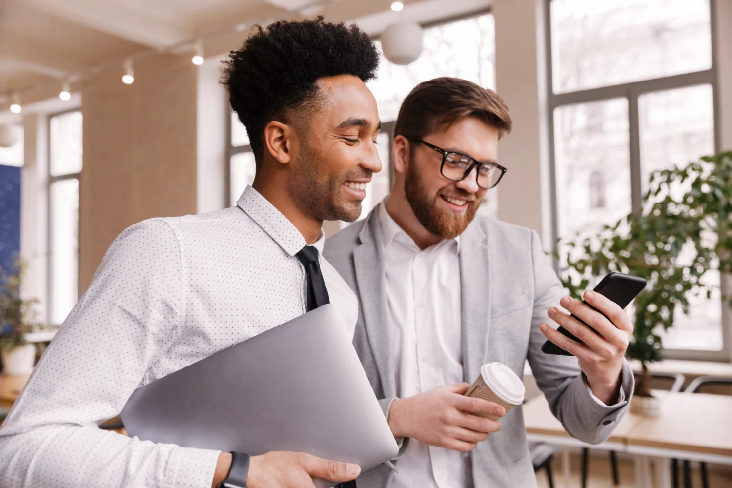 Dois homens em pé olhando para tela de um celular